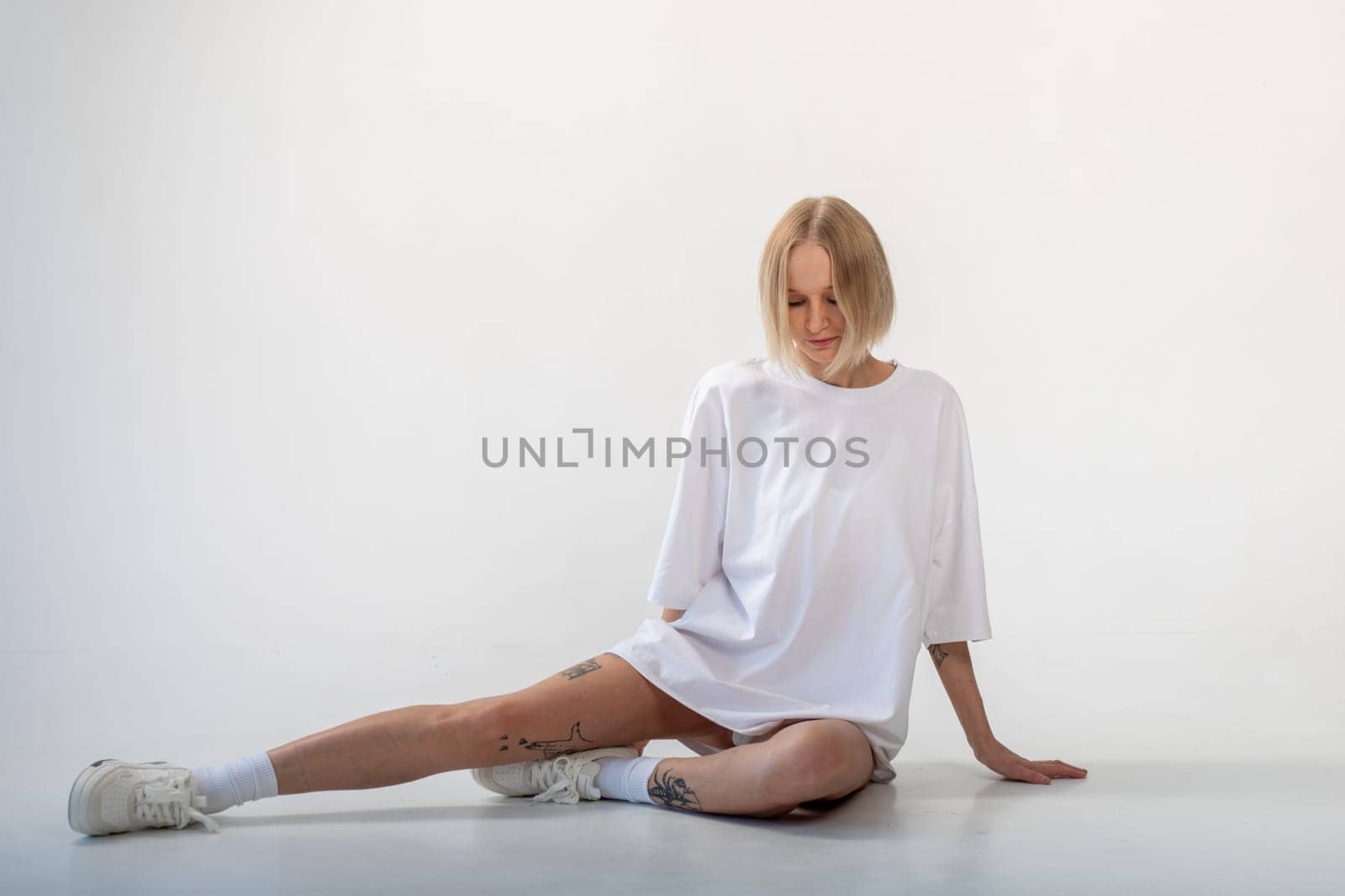 Beautiful girl in a white oversized t-shirt posing on a white background. High quality photo