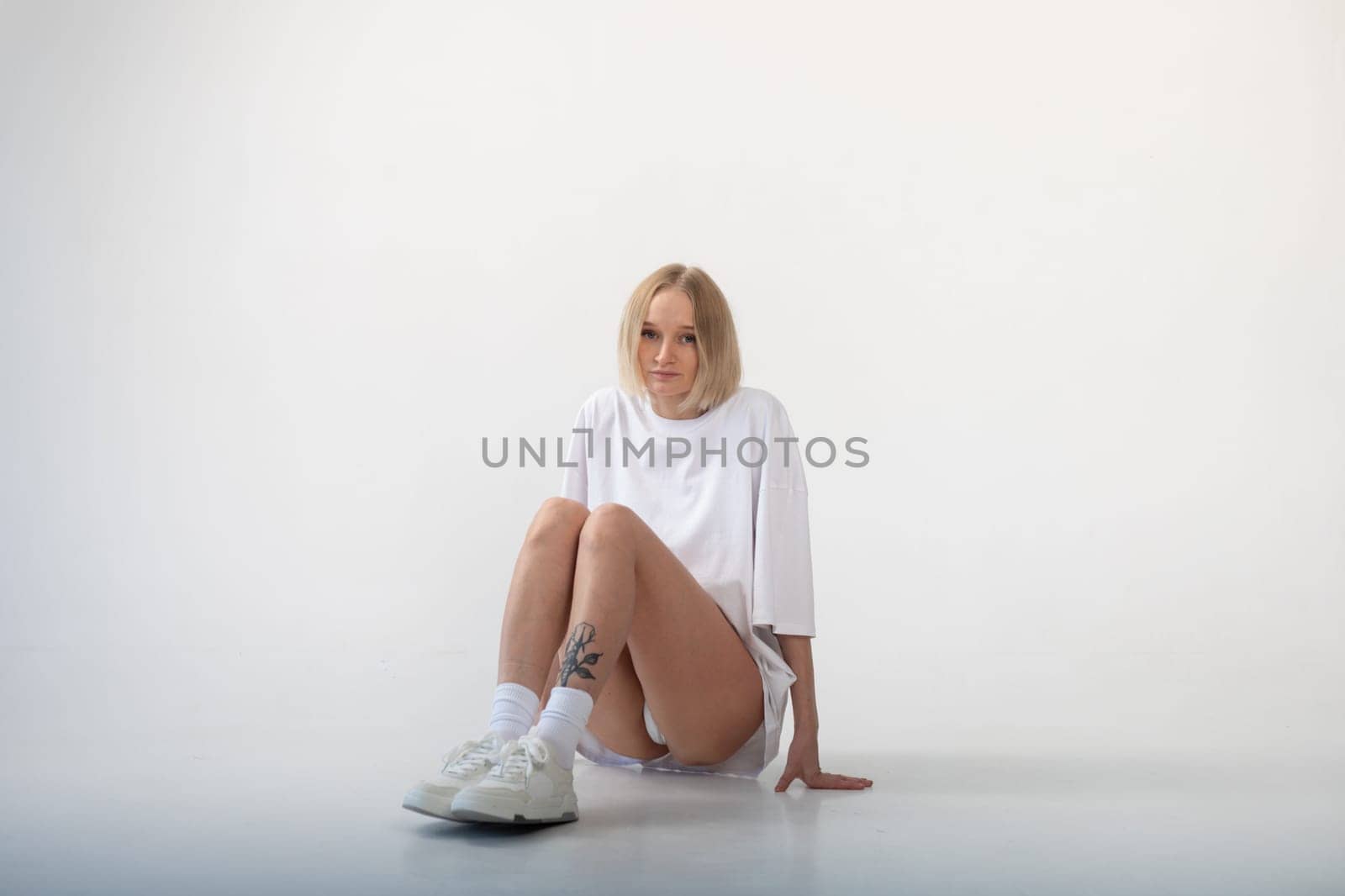 Beautiful girl in a white oversized t-shirt posing on a white background. High quality photo