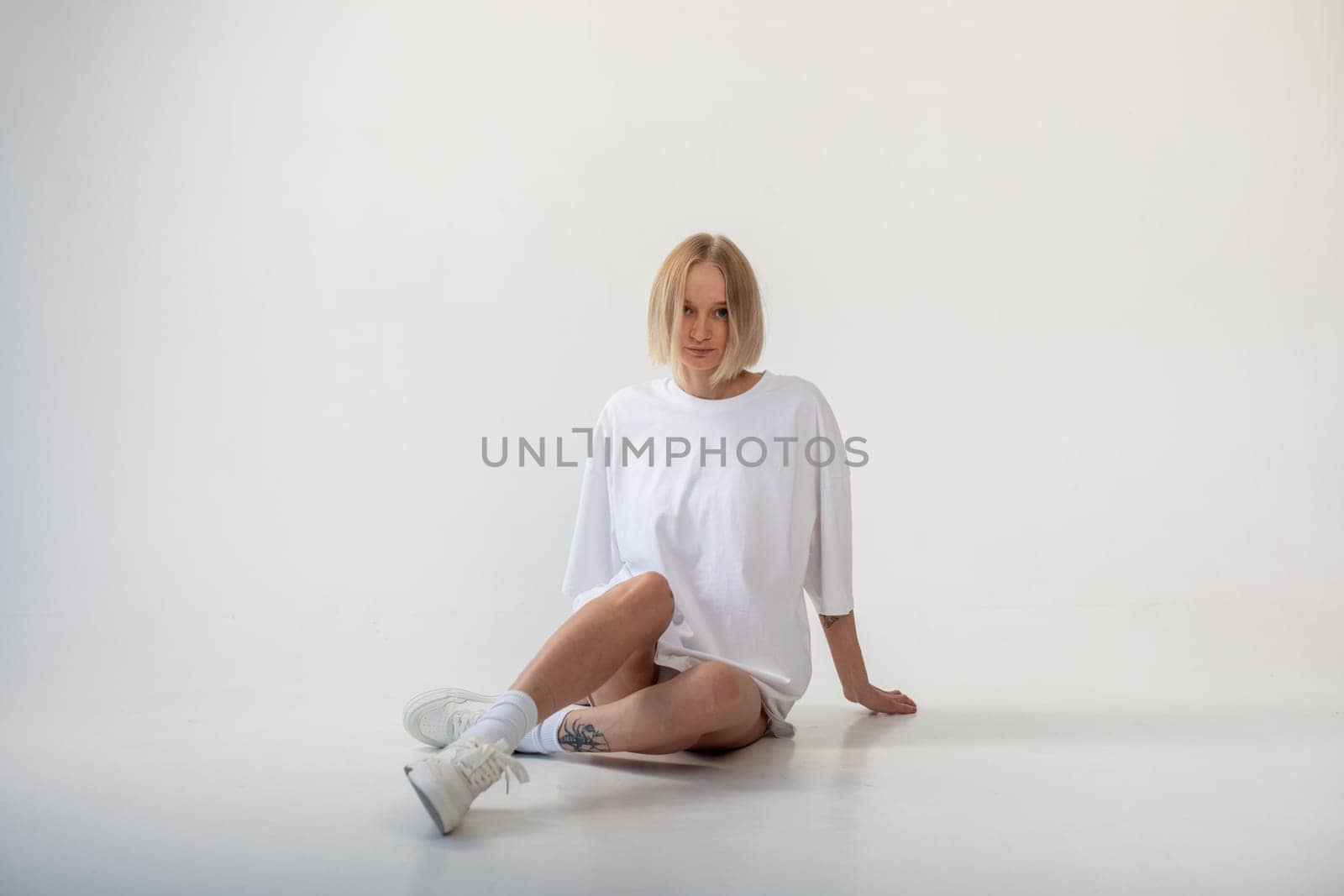 Beautiful girl in a white oversized t-shirt posing on a white background. High quality photo