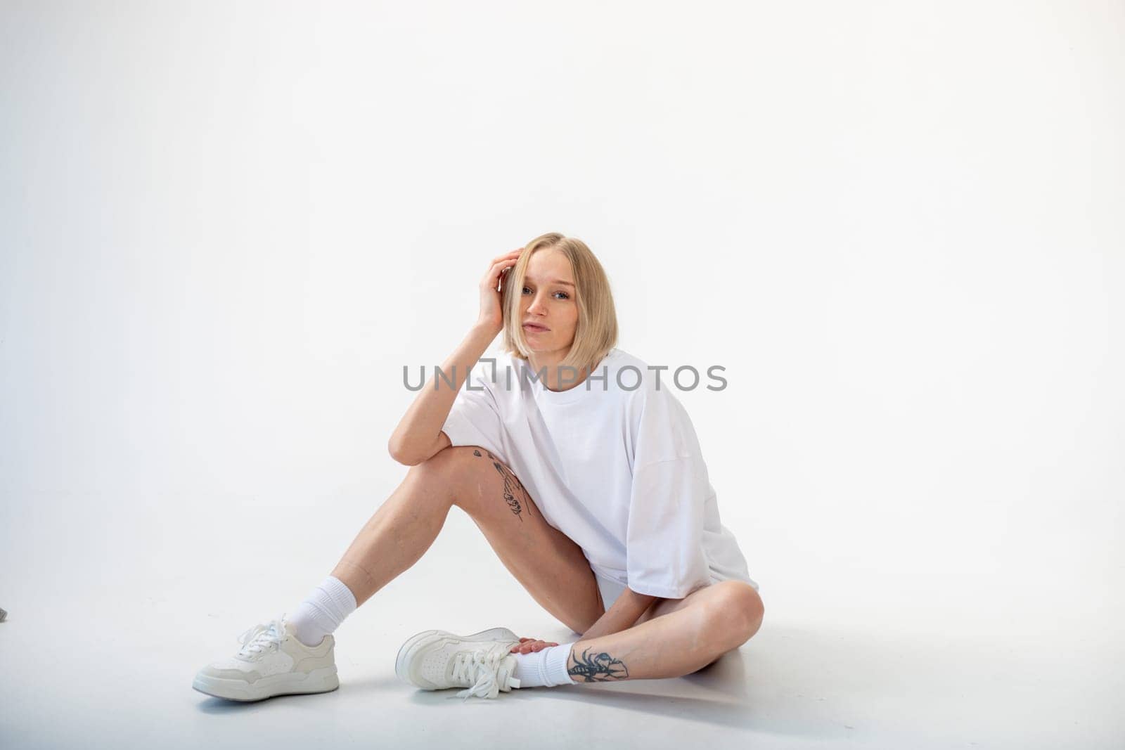 Beautiful girl in a white oversized t-shirt posing on a white background. High quality photo