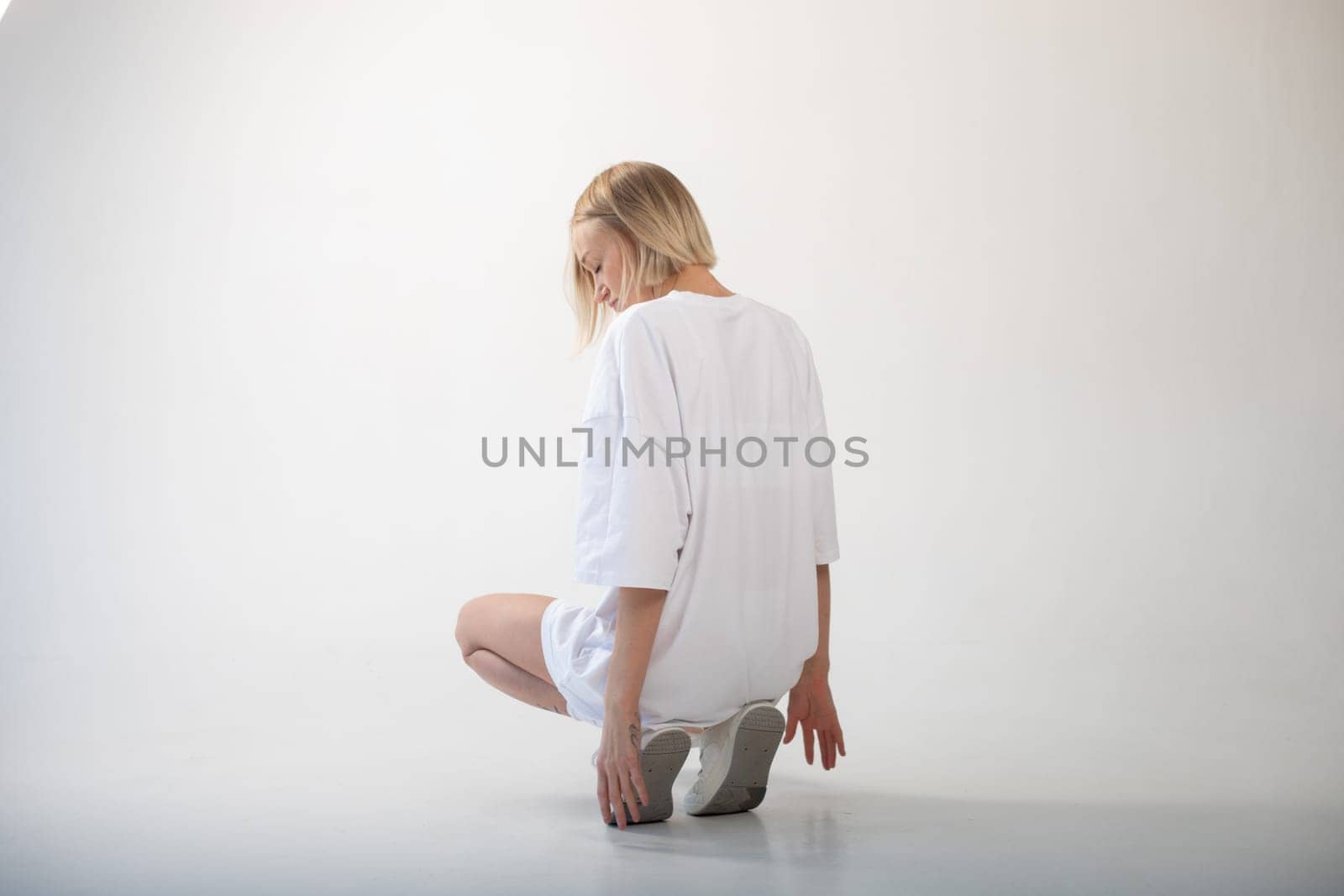 Beautiful girl in a white oversized t-shirt posing on a white background. High quality photo