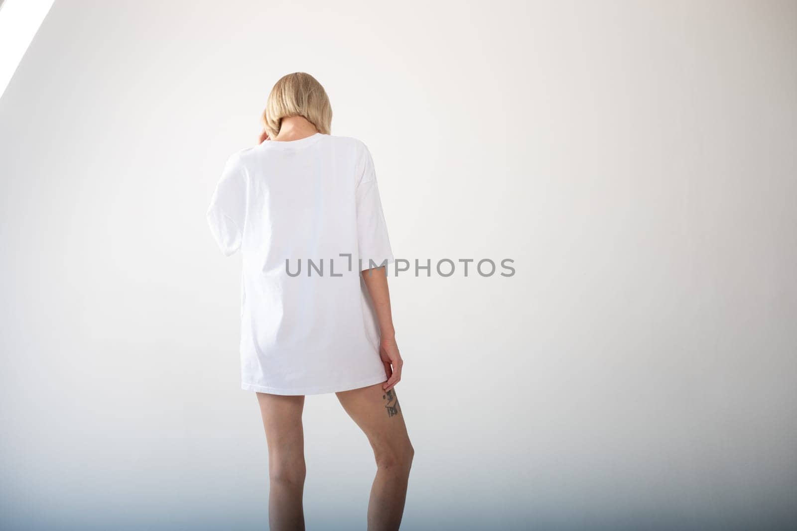 Beautiful girl in a white oversized t-shirt posing on a white background. High quality photo