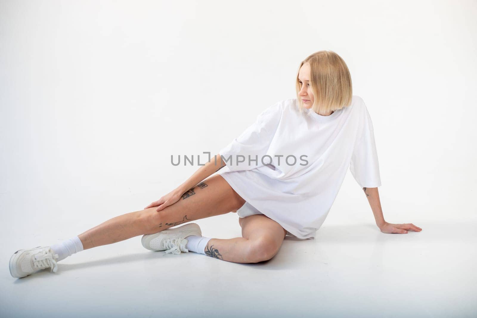 Beautiful girl in a white oversized t-shirt posing on a white background. High quality photo