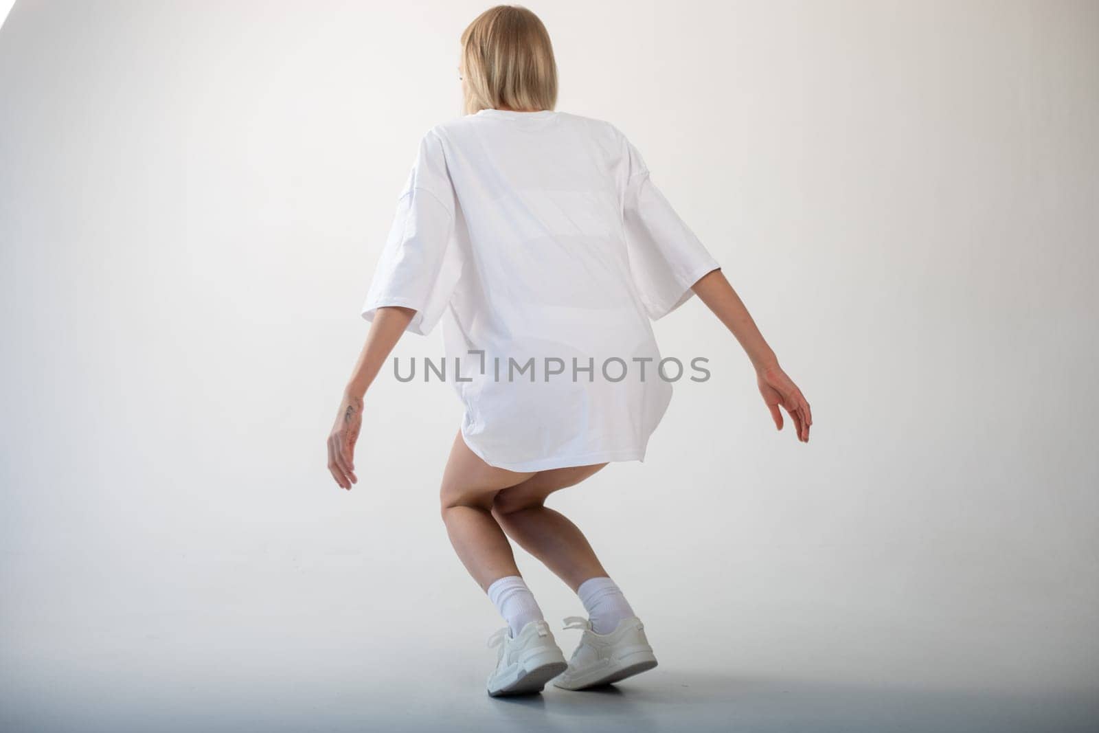 Beautiful girl in a white oversized t-shirt posing on a white background. High quality photo