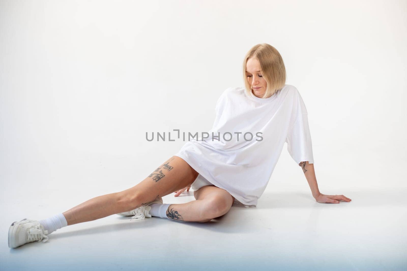 Beautiful girl in a white oversized t-shirt posing on a white background. High quality photo