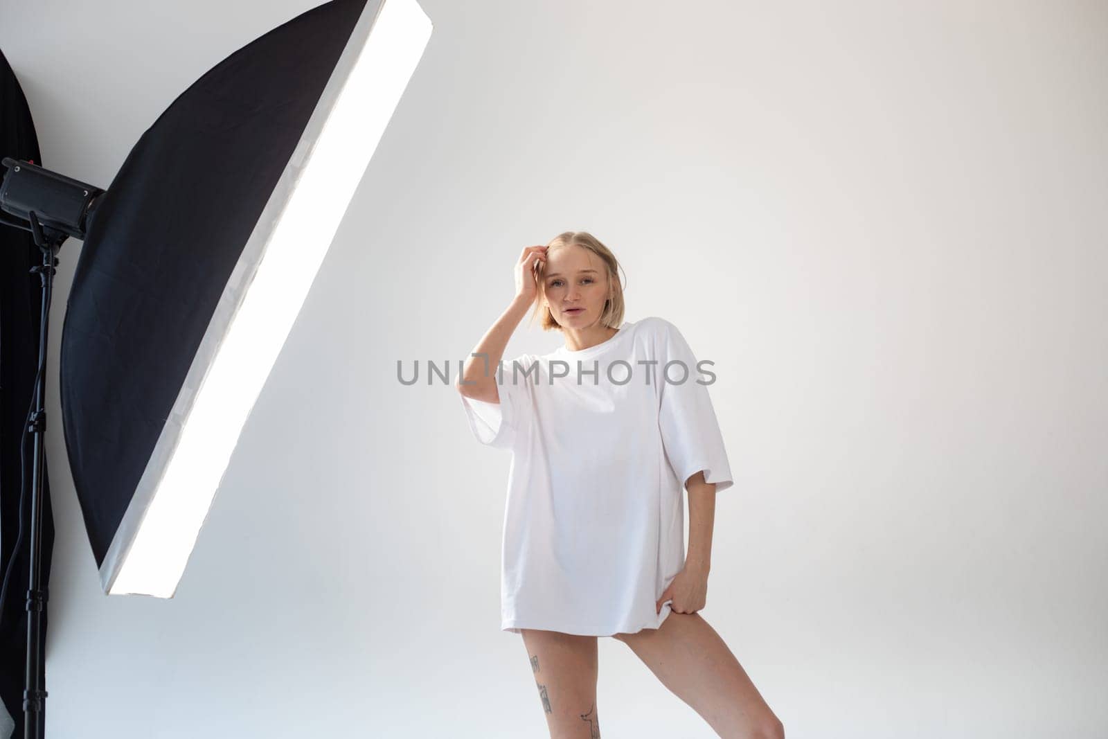 Beautiful girl in a white oversized t-shirt posing on a white background. High quality photo