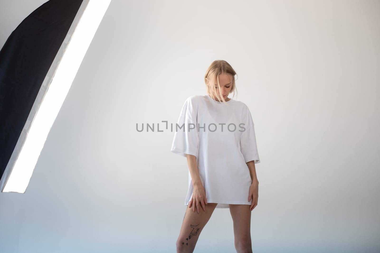 Beautiful girl in a white oversized t-shirt posing on a white background. High quality photo