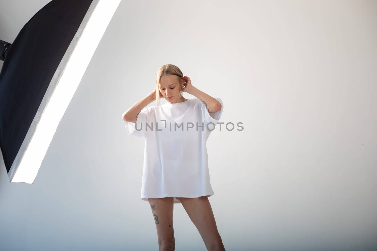 Beautiful girl in a white oversized t-shirt posing on a white background. High quality photo