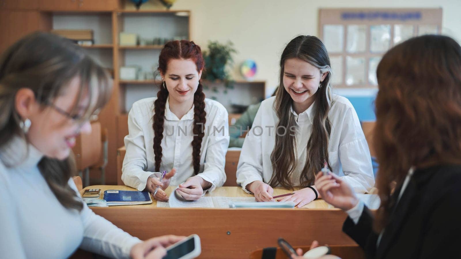 High school girls at a desk in the classroom between classes. by DovidPro