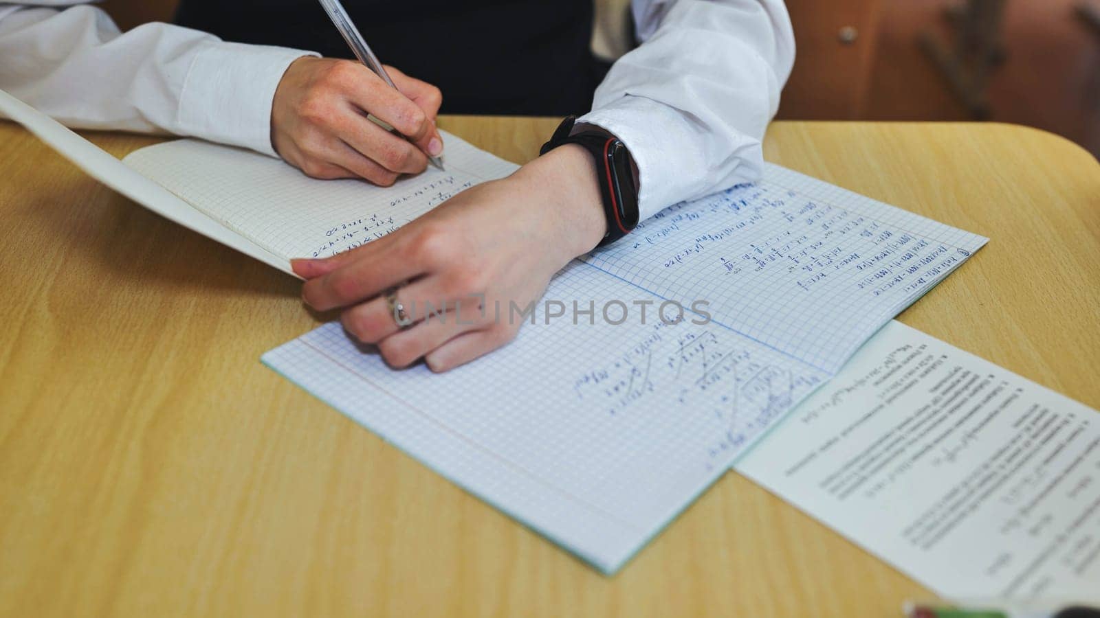 A girl student writes math formulas in a notebook. Notebook close-up. by DovidPro