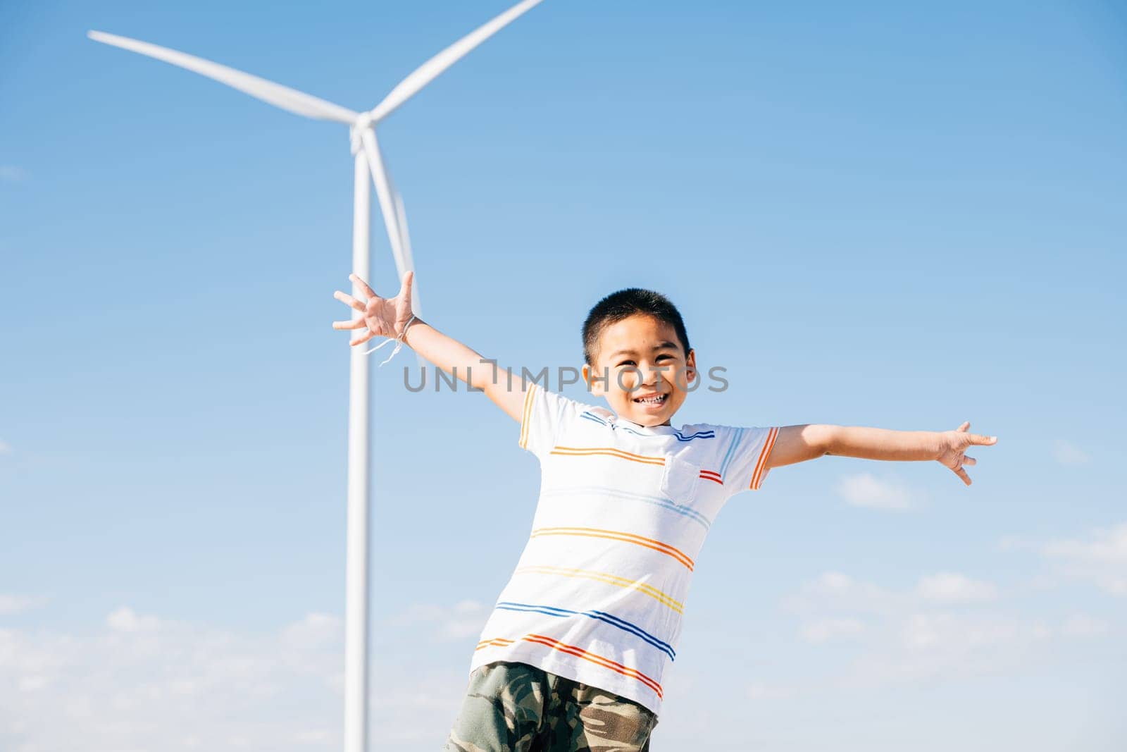 A portrait of a happy boy amidst a wind farm. Joyful family time in nature's embrace embracing clean energy and playful moments near windmills. Smiling child enjoying nature's escape.