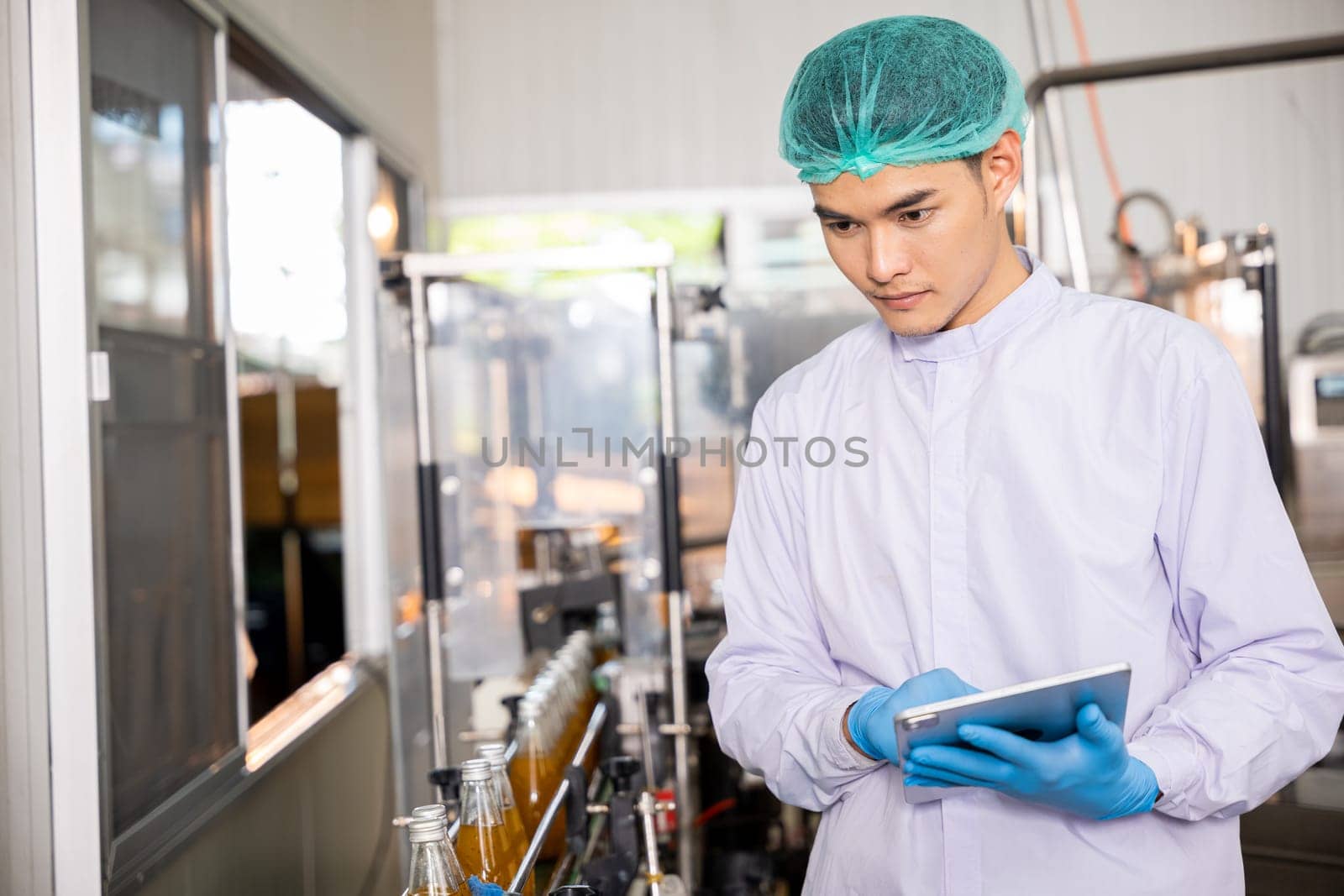 Quality control officer inspects beverage bottling factory line with tablet ensuring top-notch quality by Sorapop
