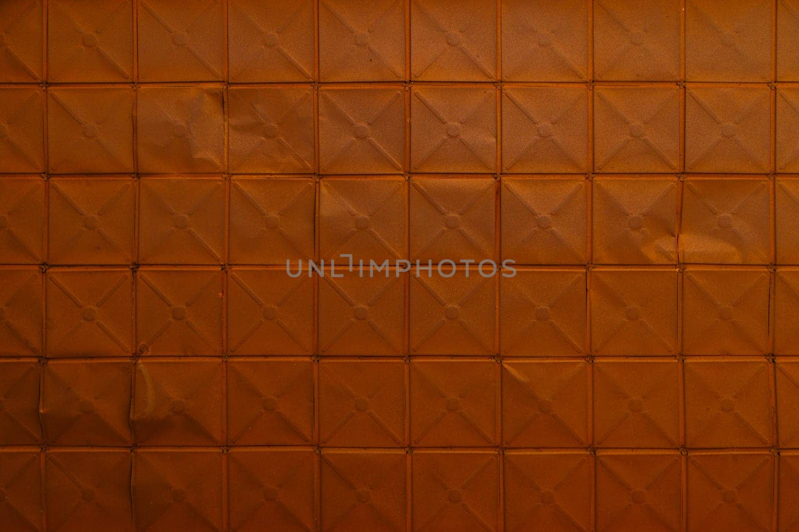 full-frame background and texture of square stamped sheet metal tiles with diagonal ribs.