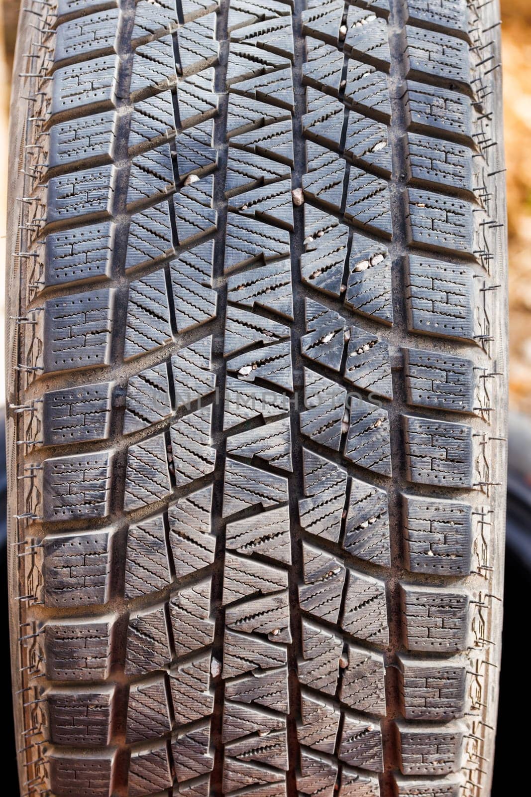 small rocks stuck in car tire tread, closeup.