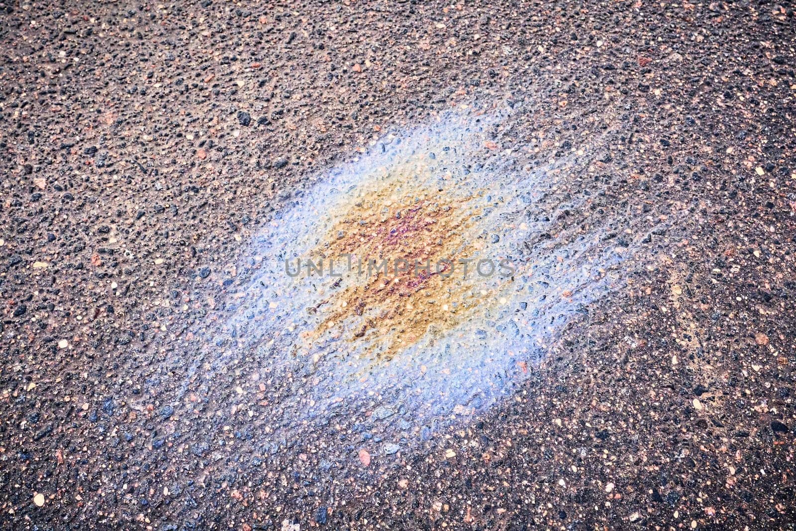 Color gasoline fuel spot on black asphalt, industrial pollution concept