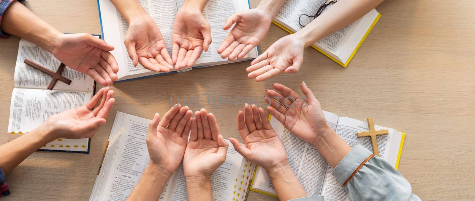 Cropped image of diversity people hand praying together at wooden church on bible book. Group of believer hold hand together faithfully. Concept of hope, religion, faith, god blessing. Burgeoning.