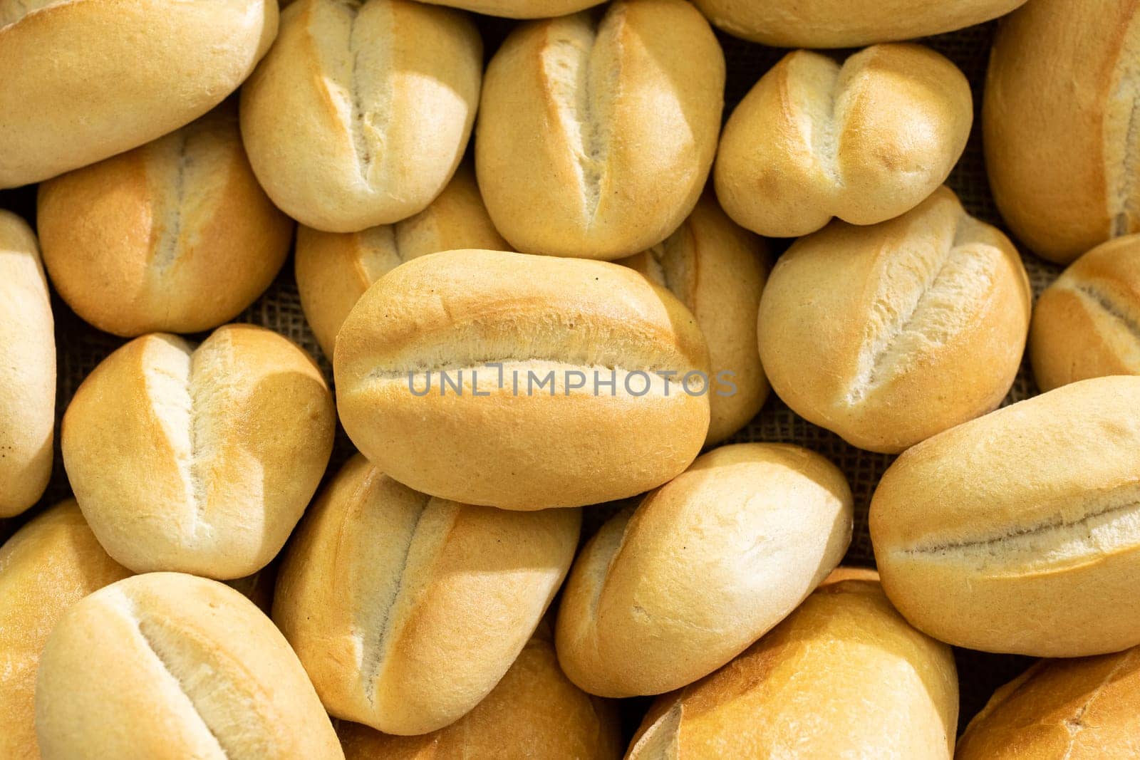 Many rolls of the same size and type from a traditional bakery lie next to each other, all baked in the oven in white wheat flour.