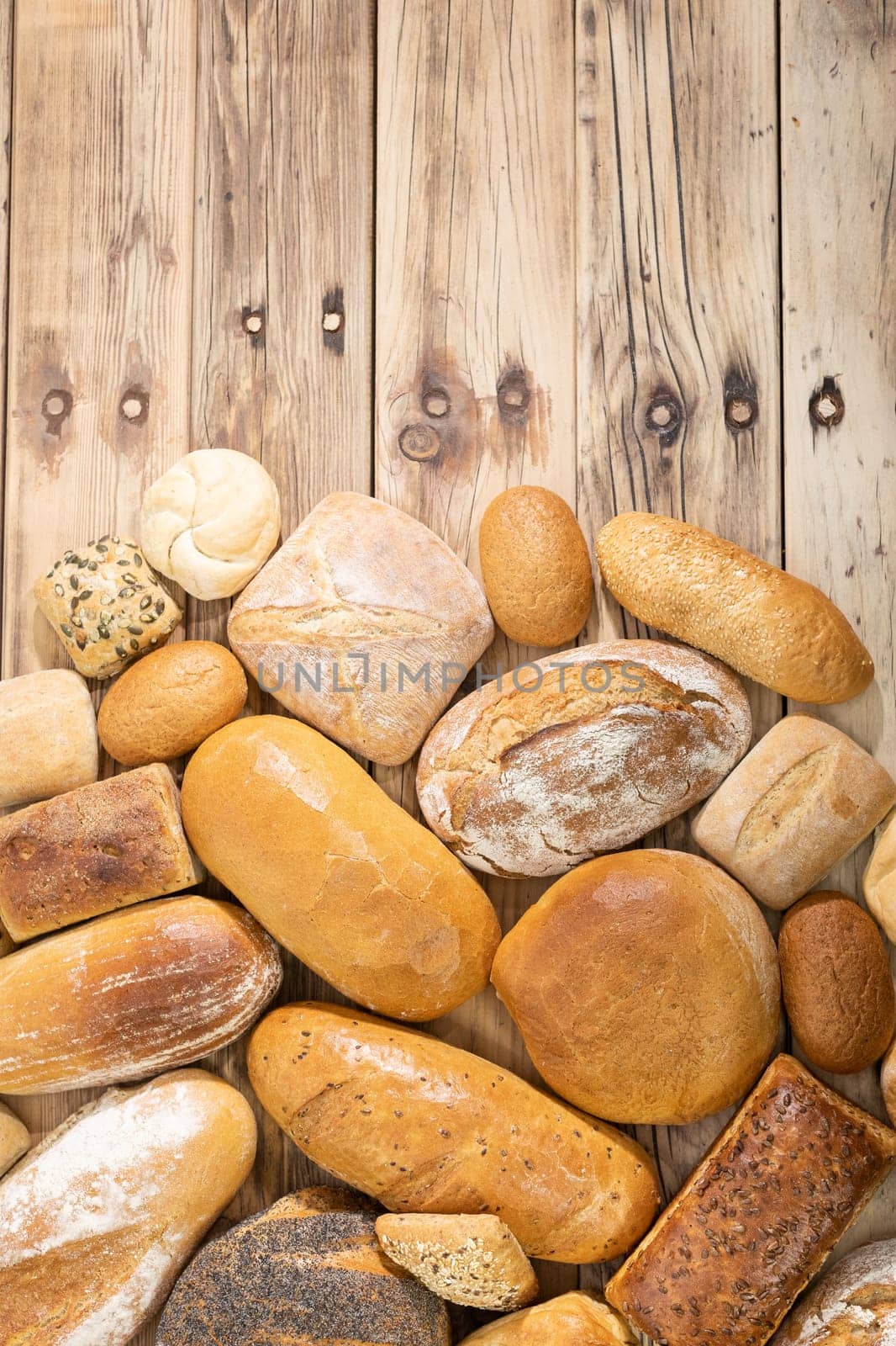 On the old wooden counter, the bakery store has gathered all the types of bread that it prepares in its bakery. View from above.