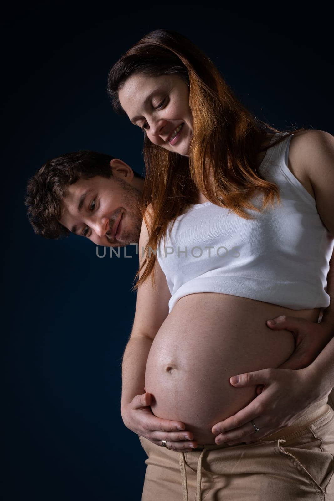 The husband and wife look at the large pregnancy belly and enjoy the fruit of their love immensely. Ninth month of pregnancy. Unborn baby in the belly.