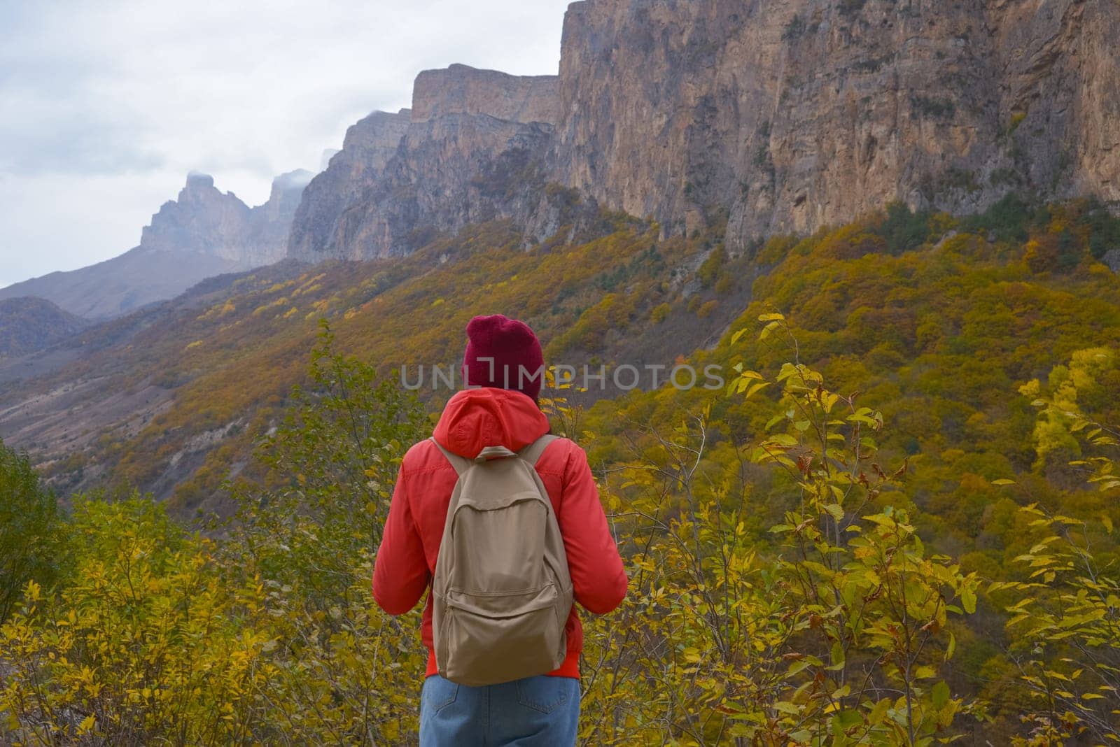 Brunette woman with a backpack on her back outdoors exploring the Caucasus Mountains in Russia, traveling, lifestyle, hiking, active autumn holidays, hiking by Ekaterina34
