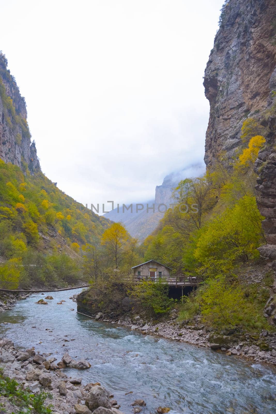 A small house near a mountain river and the foot of the misty mountains. North Caucasus, Russia. by Ekaterina34