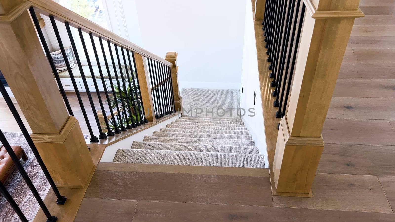 The image captures the detail of a well-designed modern staircase, lined with plush beige carpet, complemented by white walls and wooden balusters.