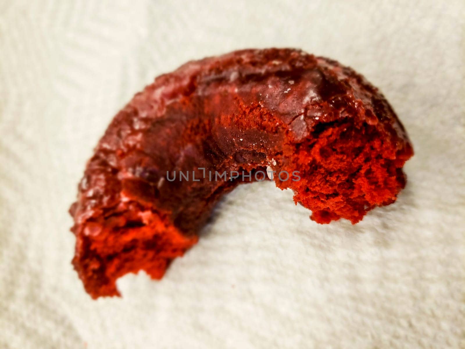 View of a Partially-eaten Red Velvet Donut Sitting on a Paper Napkin