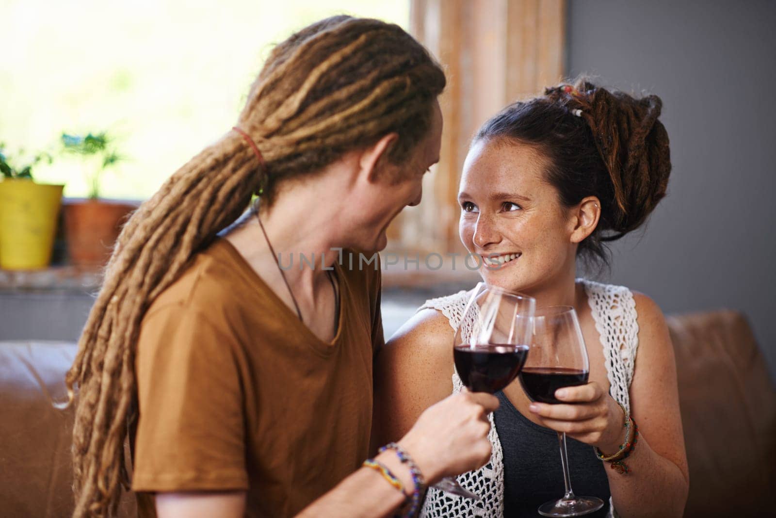 Couple, wine and cheers for love, romance and joy for romantic, dating and relationship together for unwind. Boyfriend, girlfriend and rasta with glass and smile and relax with drink in lounge.