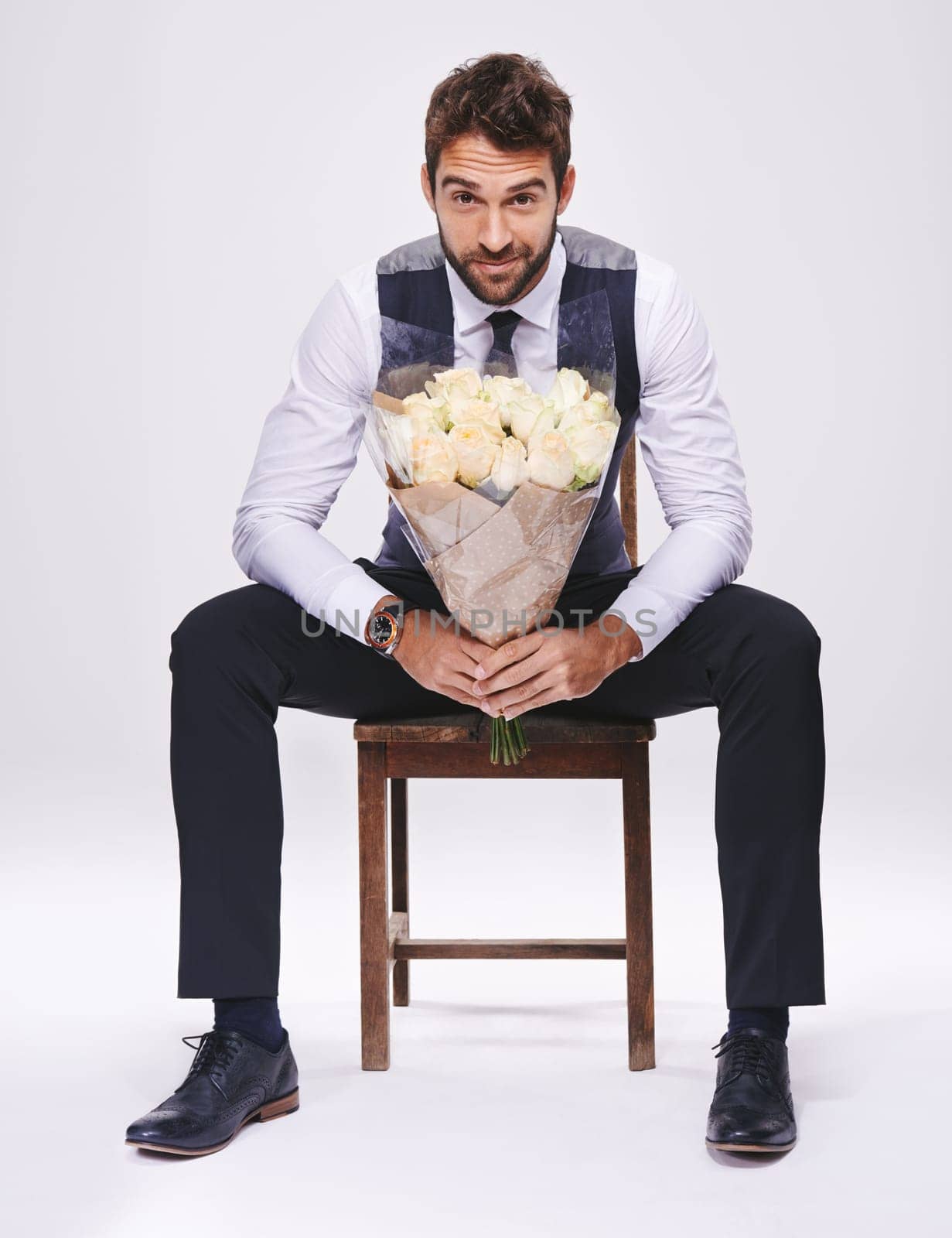Studio, portrait and man with chair, bouquet and date for style and fashion. Gentleman, designer and romance with flowers, confidence and proud ambition with suit isolated on white background by YuriArcurs