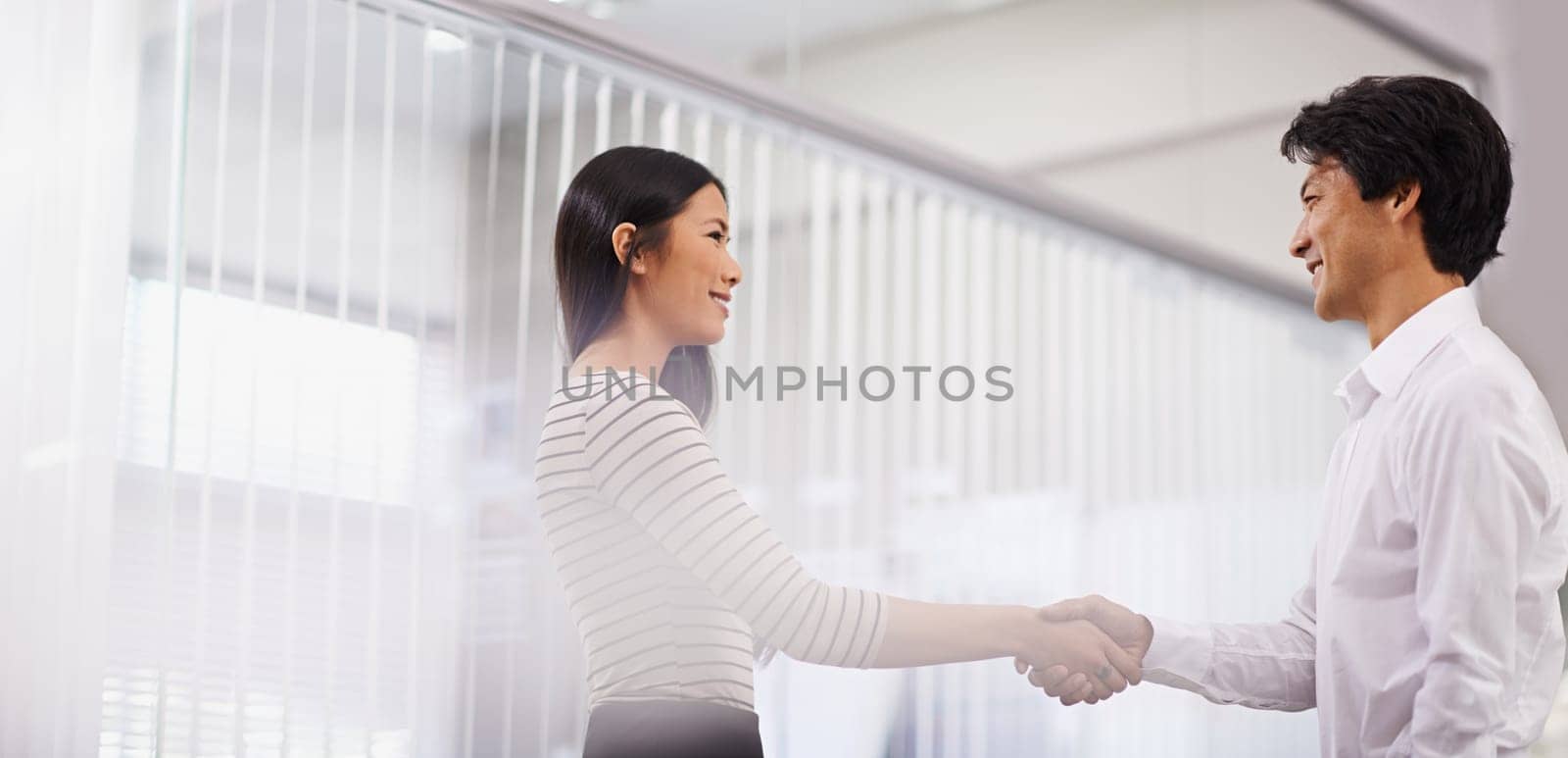 Happy, business people and handshake with team for meeting, agreement or deal together at the office. Young asian man and woman shaking hands for b2b, greeting or partnership at the workplace by YuriArcurs