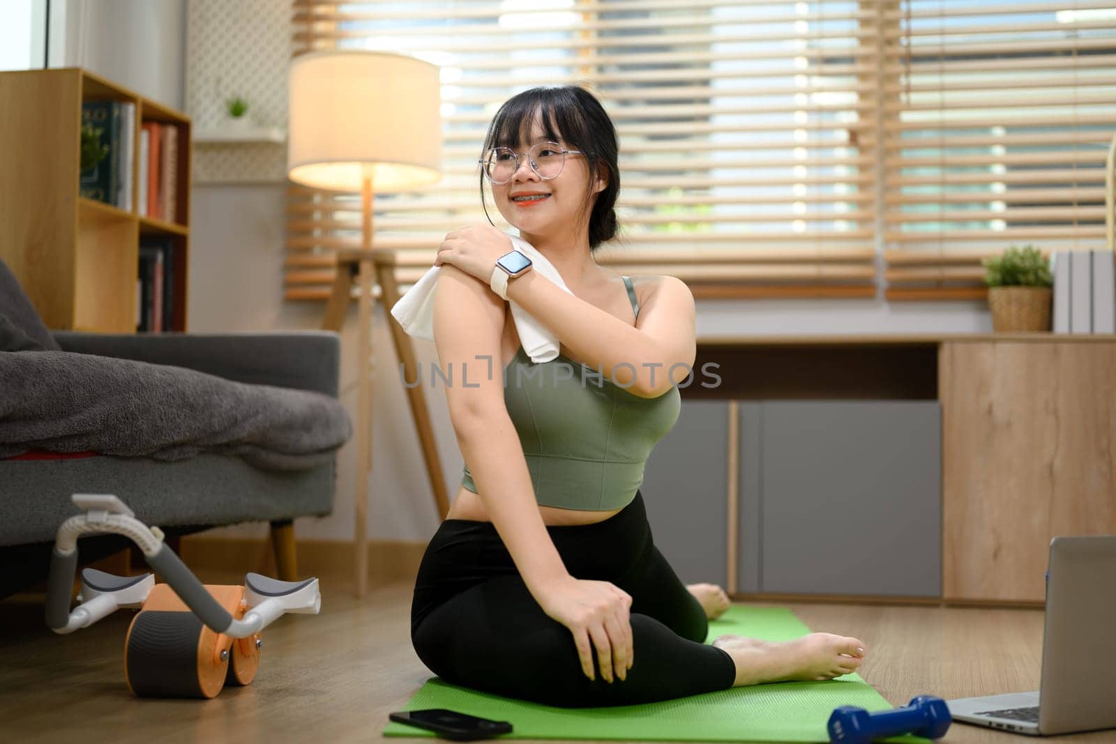 Pretty young woman practicing yoga in living room. Healthy lifestyle concept.