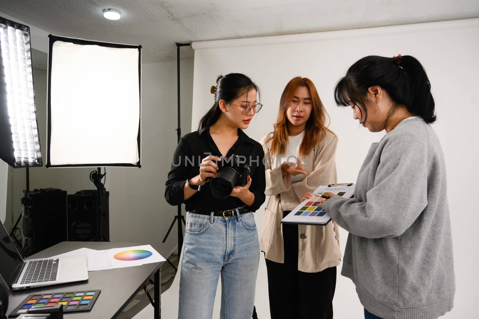 Production team and photographer working together in studio with camera and lighting equipment.