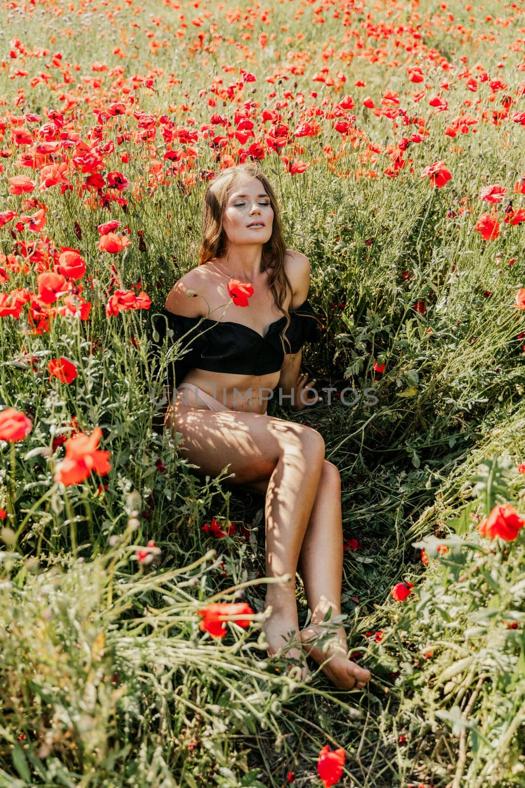 Woman poppies field. portrait of a happy woman with long hair in a poppy field and enjoying the beauty of nature in a warm summer day