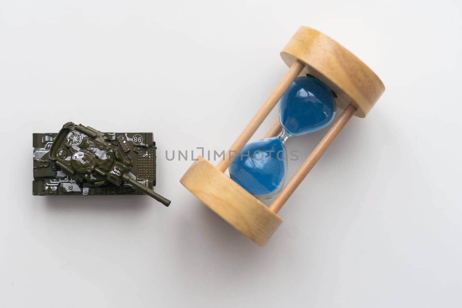 The plastic tank toys on the floor next to an hourglass. High quality photo