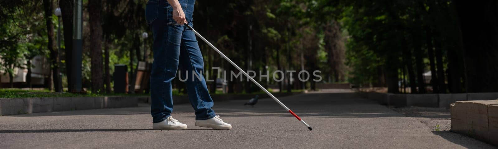 Blind woman crosses the street with the help of a tactile cane. Wide screen. by mrwed54