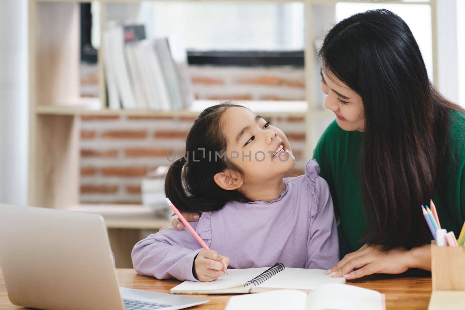 A woman is helping a young girl with her homework by ijeab