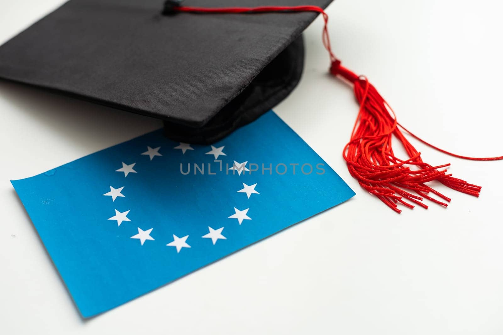 Graduation cap with red tassel isolated on white background by Andelov13