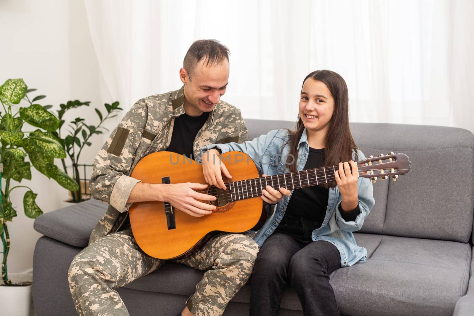 a veteran and his daughter play the guitar by Andelov13