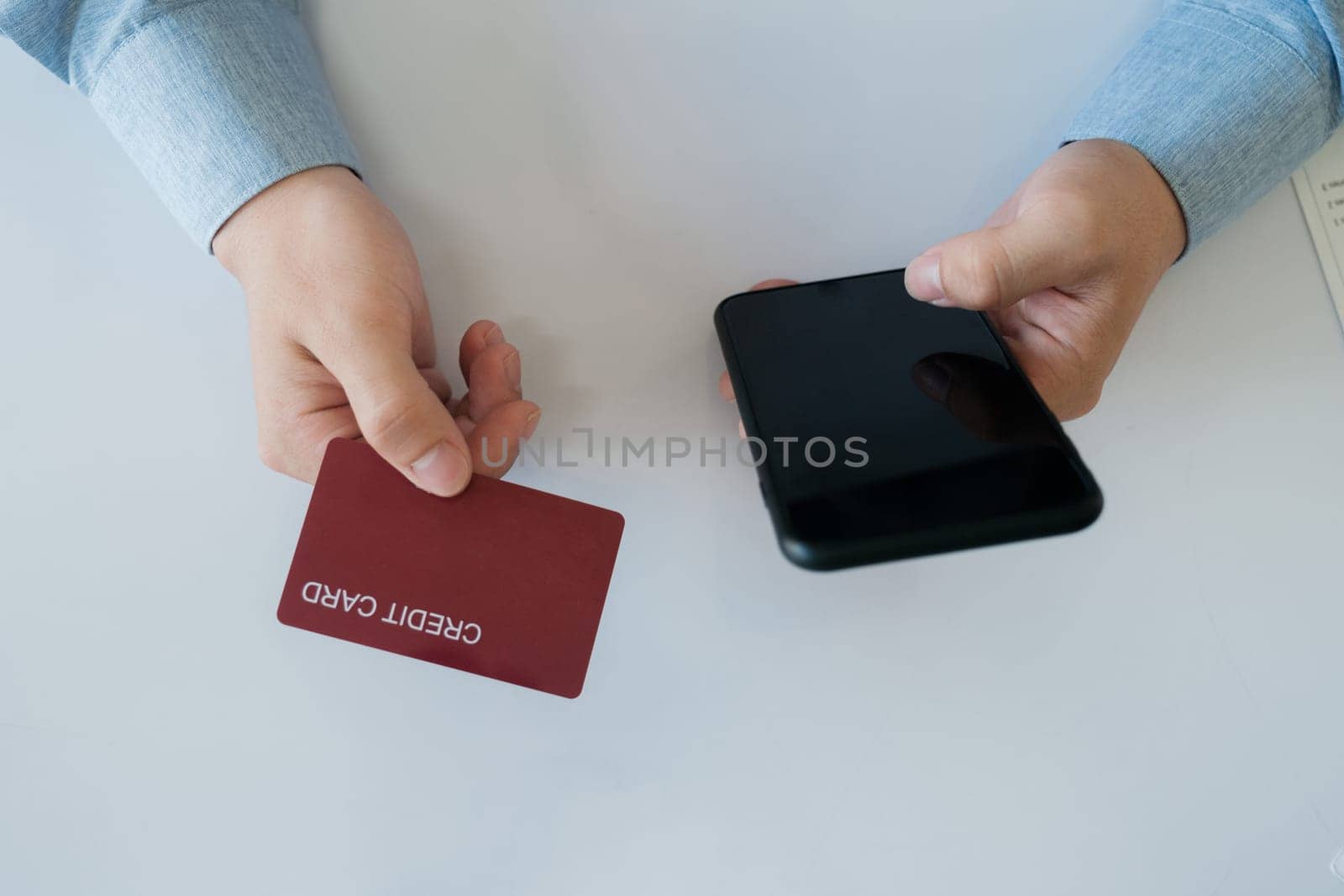 A man is using his phone to pay for something with a credit card by ijeab