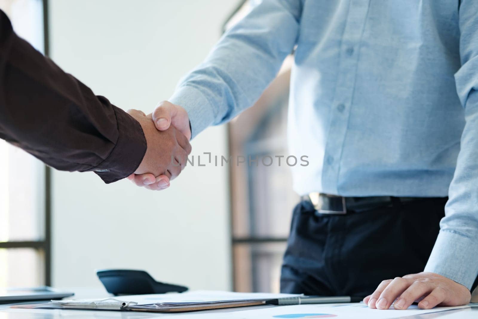 The business deal was successful and businessmen shake hands and congratulate each other.