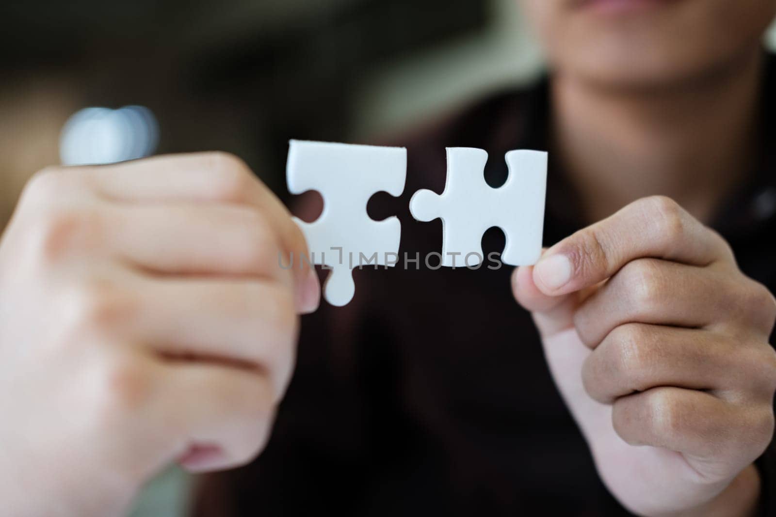 Two people holding a puzzle piece together. Concept of teamwork and collaboration. by ijeab