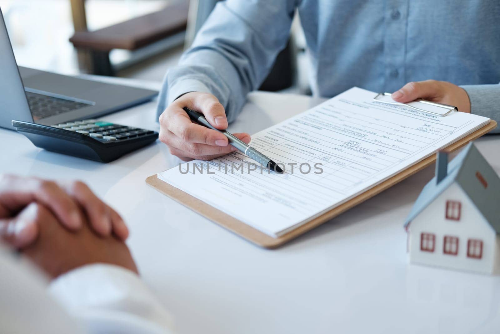 A real estate agent is pointing at a loan contract with a pen. To allow customers who agree to buy, rent, or invest in housing to sign the document.