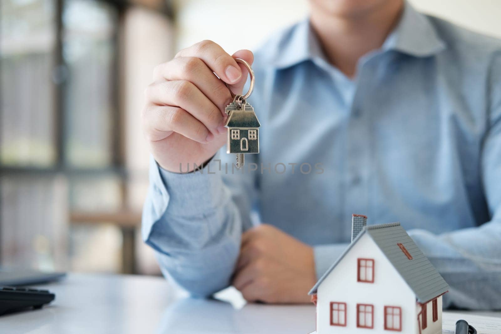 A real estate agent is handing home keys to a customer. After taking out a loan for buying and selling a house. Credit business, savings, real estate investment