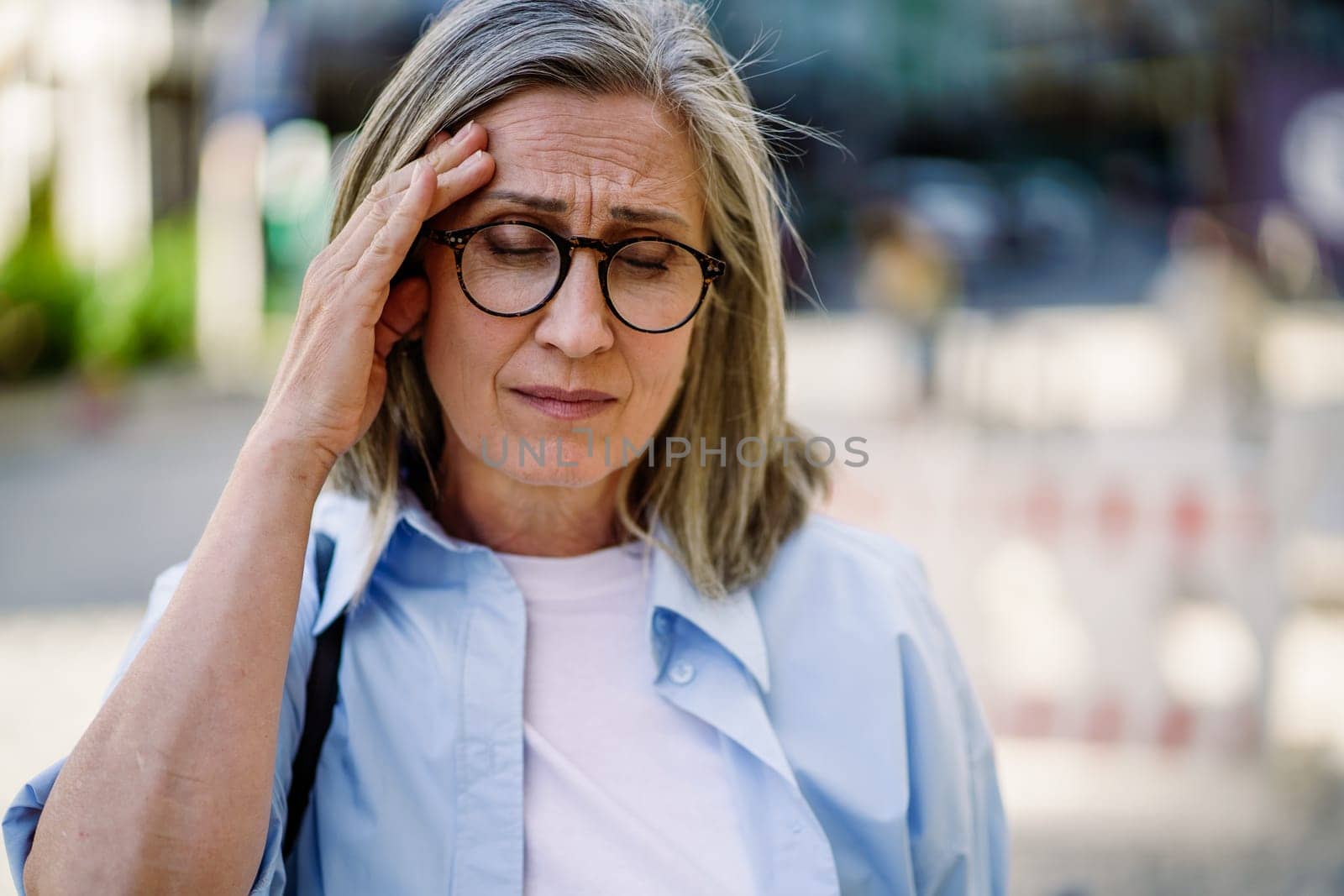 A woman wearing glasses is shown holding her head in this straightforward image.