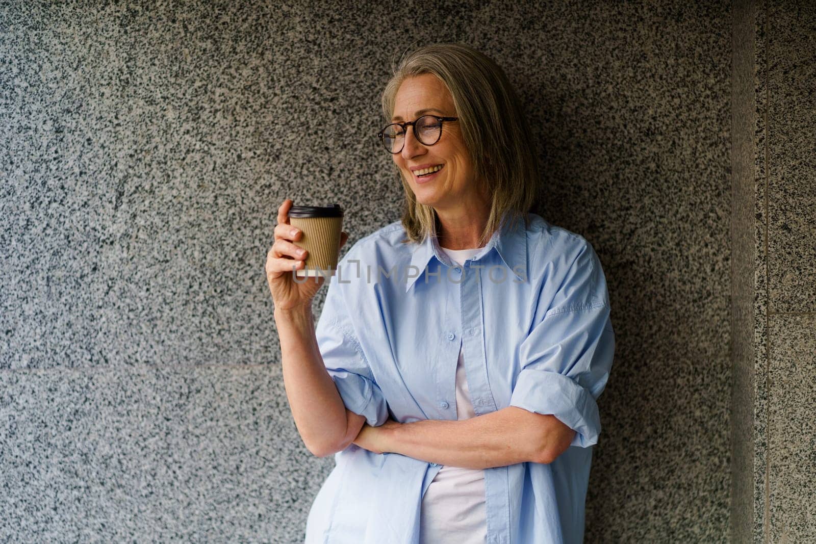 Woman With Glasses Holding Coffee Cup by LipikStockMedia