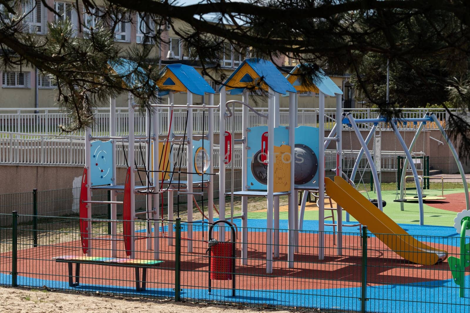 A separate and fenced play area for children with a safe, colorful surface. Children's outdoor playground.