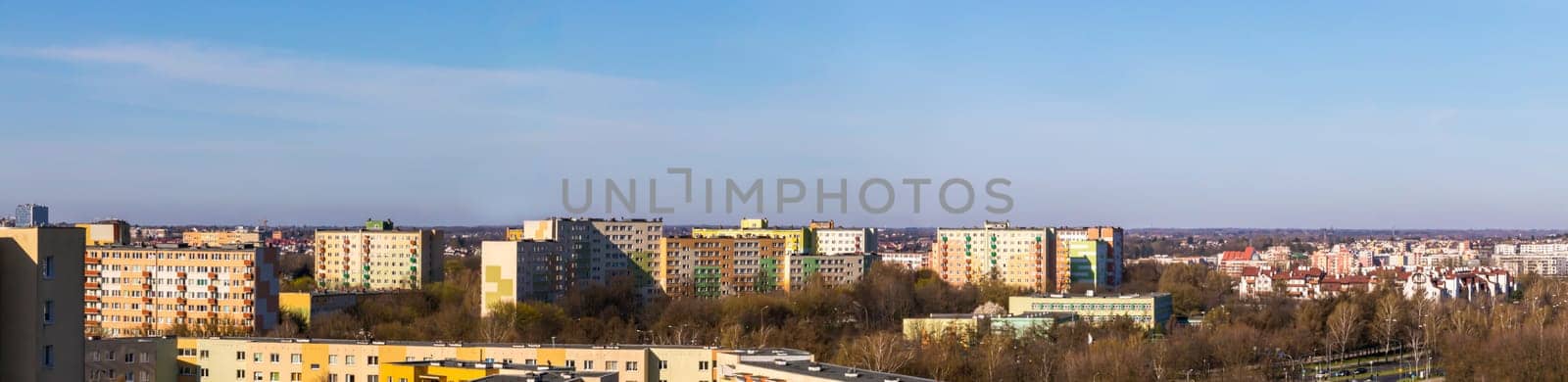 The whole city is bathed in the morning sun as part of Lublin's panorama. Lots of skyscrapers and lower buildings sufficient among the trees in early spring.