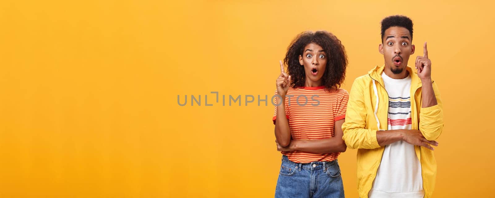 The both got perfect idea at same time. Amazed and excited creative charismatic african american man and woman raising index fingers in eureka gesture opening mouth while adding suggestions by Benzoix