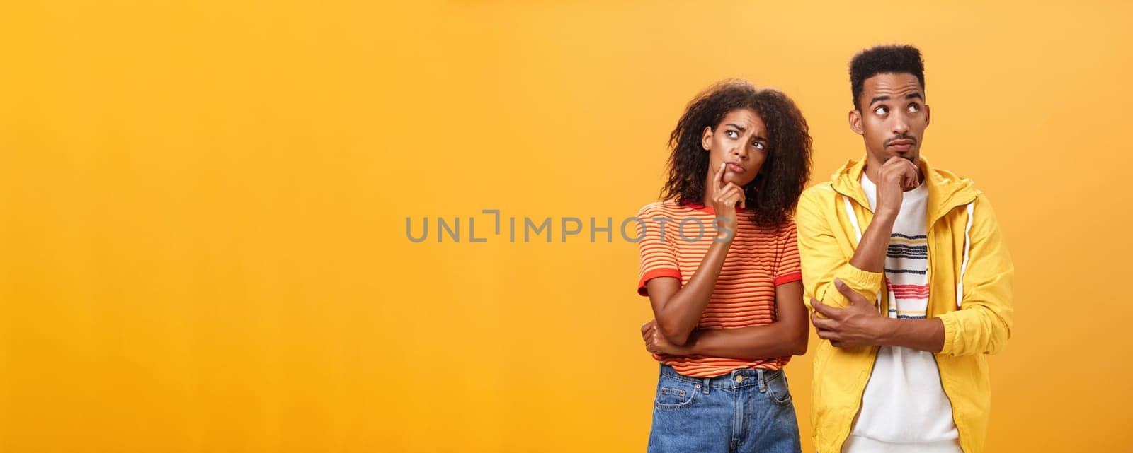 Two brains better than one. Thoughtful couple of african american friends in stylish urban outfit standing in thinker pose looking up determined and focused making up plan how spend evening. Relationship concept