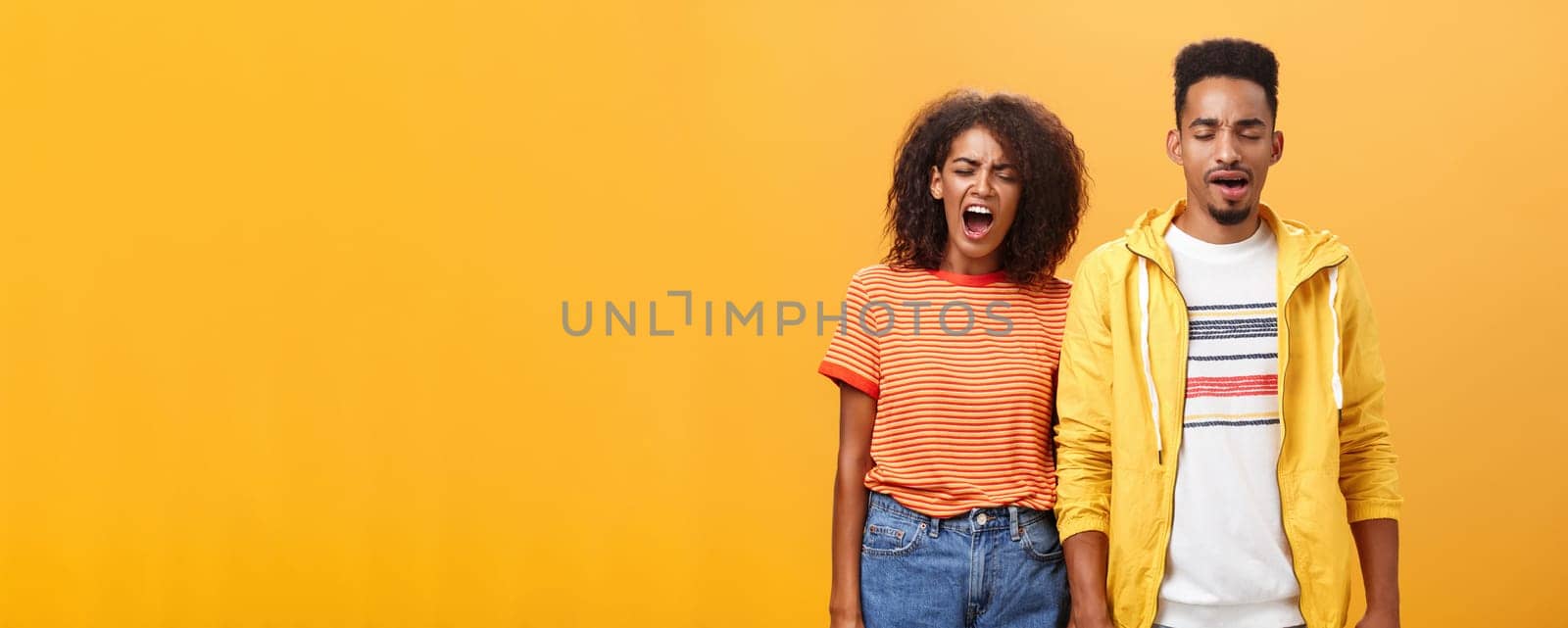 Stylish and attractive brother and sister over orange background yawning with closed eyes and tired expression being drained and exhausted after dealing with house chores cleaning mess after party by Benzoix